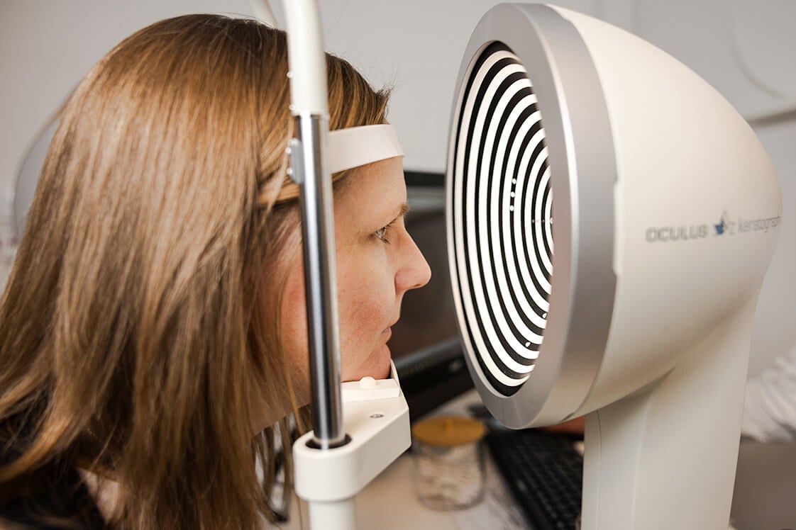 Kvinne sjekker øynene i apparat hos optiker